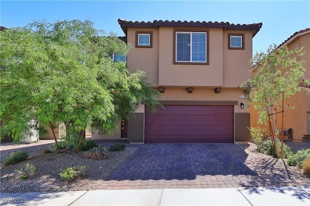 view of front facade with decorative driveway, a garage, stucco siding, and a tile roof
