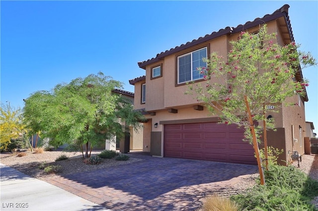 mediterranean / spanish home featuring a tiled roof, decorative driveway, an attached garage, and stucco siding