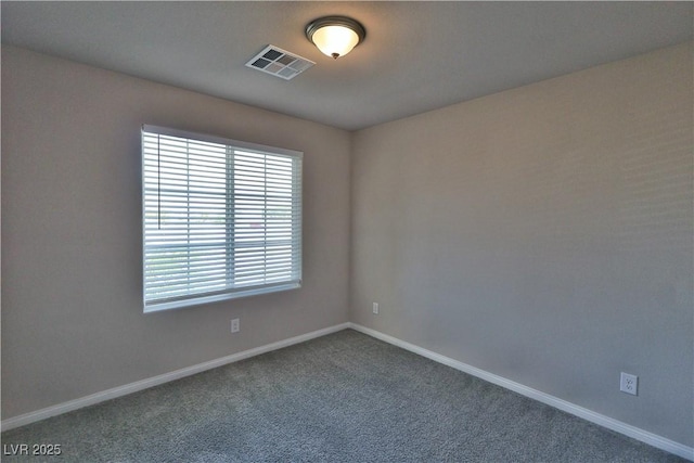 spare room featuring baseboards, dark carpet, and visible vents