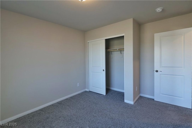 unfurnished bedroom with baseboards, dark carpet, and a closet