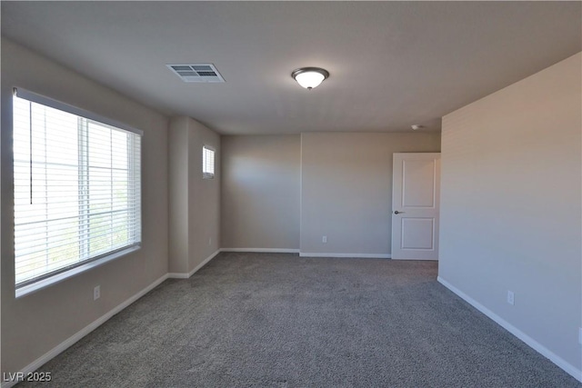 carpeted spare room featuring baseboards and visible vents