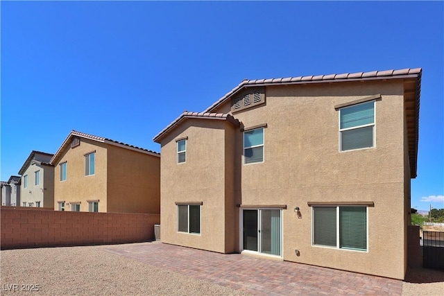 rear view of house with fence, a patio, stucco siding, and a tile roof