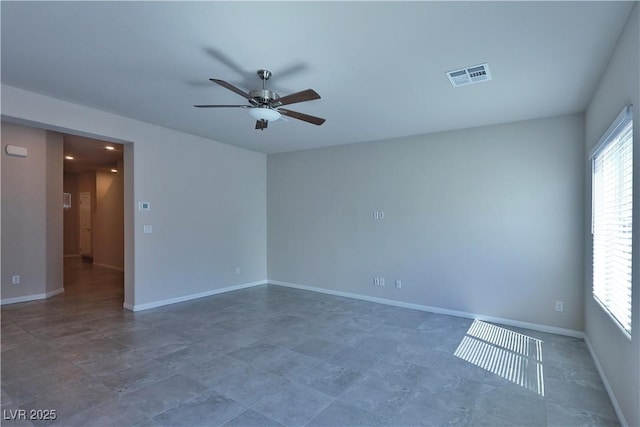 empty room featuring baseboards, ceiling fan, and visible vents