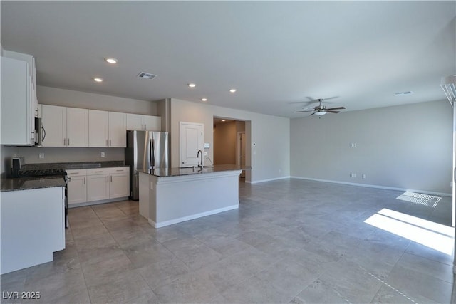 kitchen featuring ceiling fan, appliances with stainless steel finishes, a kitchen island with sink, white cabinetry, and visible vents