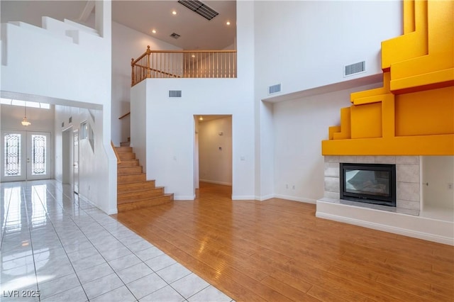 787 Craigmark Ct, Henderson, NV 89002 - unfurnished living room with a towering ceiling, stairway, a fireplace, light wood-style floors, and baseboards