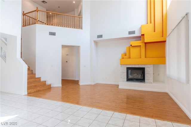 787 Craigmark Ct, Henderson, NV 89002 - unfurnished living room featuring light wood-style floors, a towering ceiling, stairs, a fireplace, and baseboards