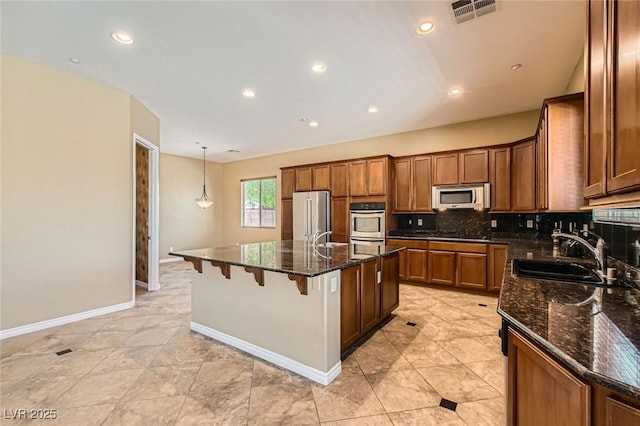 3910 Internet Ave, North Las Vegas, NV 89031 - kitchen with appliances with stainless steel finishes, a sink, decorative backsplash, a center island with sink, and dark stone countertops
