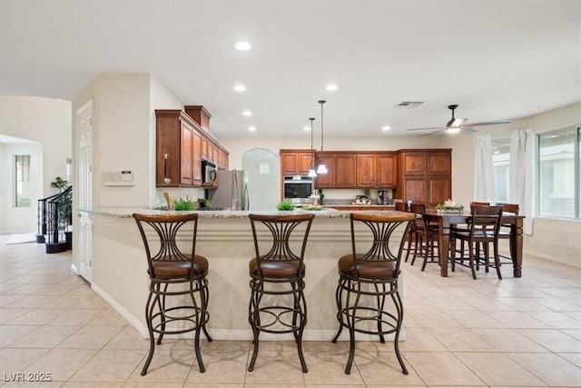 6335 Iginlas Goal Ave, Las Vegas, NV 89131 - kitchen featuring visible vents, a peninsula, light tile patterned flooring, a breakfast bar, and stainless steel appliances