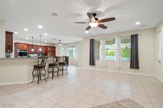 6335 Iginlas Goal Ave, Las Vegas, NV 89131 - kitchen with light tile patterned flooring, stainless steel oven, a ceiling fan, recessed lighting, and a kitchen bar