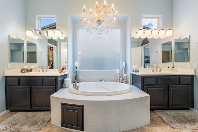 bathroom with an inviting chandelier, a sink, a garden tub, and two vanities