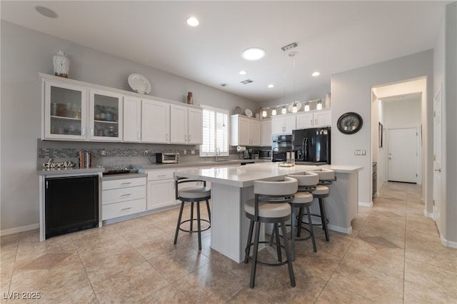 kitchen with a sink, white cabinetry, black refrigerator with ice dispenser, and light countertops