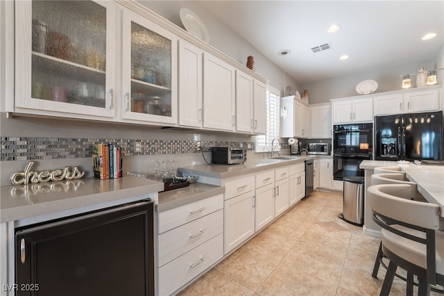 kitchen with backsplash, light tile patterned flooring, visible vents, and black appliances