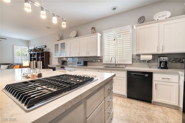 kitchen with a sink, dishwasher, stainless steel gas cooktop, light countertops, and tasteful backsplash