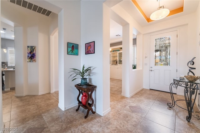 entrance foyer with arched walkways, tile patterned flooring, baseboards, and visible vents