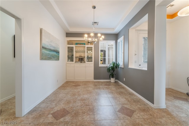 unfurnished dining area with baseboards, visible vents, a tray ceiling, and a notable chandelier