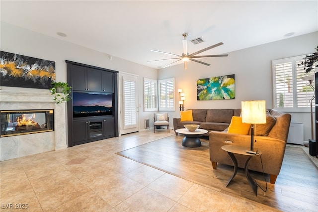 living room featuring a multi sided fireplace, ceiling fan, visible vents, and tile patterned floors