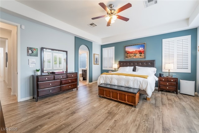 bedroom featuring baseboards, visible vents, wood finished floors, and a raised ceiling