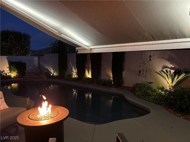 pool at twilight with a fenced in pool and an outdoor fire pit