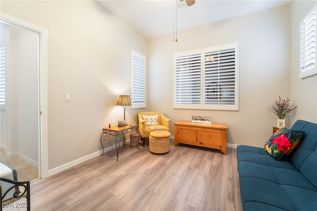 living area featuring light wood-style floors, baseboards, and a ceiling fan