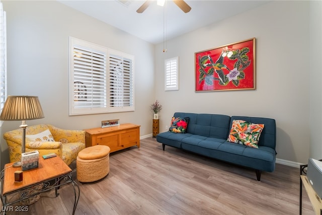 living area with baseboards, a ceiling fan, and wood finished floors