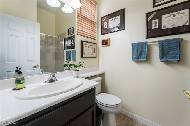 bathroom with vanity, baseboards, a shower stall, and toilet