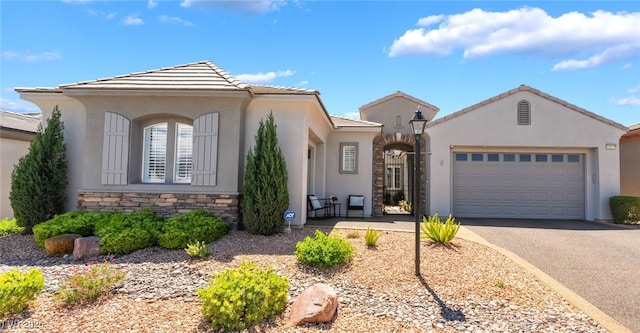 ranch-style home featuring an attached garage, stone siding, aphalt driveway, stucco siding, and a tiled roof