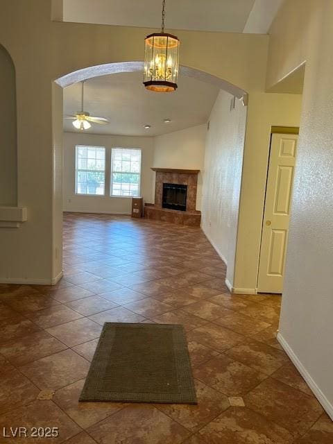 7650 Butterscotch Ct, Las Vegas, NV 89131 - unfurnished living room with arched walkways, ceiling fan, a tile fireplace, and a chandelier