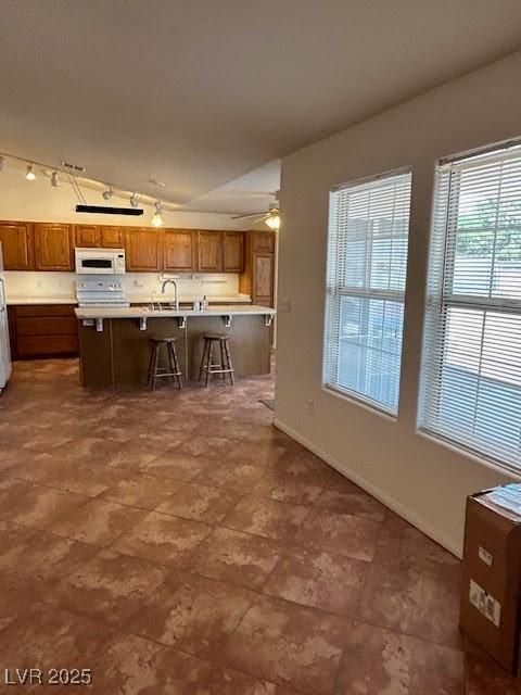 7650 Butterscotch Ct, Las Vegas, NV 89131 - kitchen with white microwave, light countertops, a breakfast bar, brown cabinets, and fridge