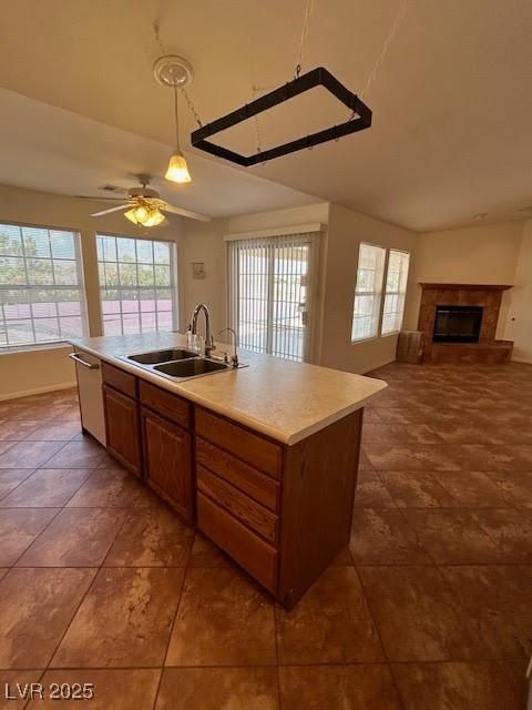 7650 Butterscotch Ct, Las Vegas, NV 89131 - kitchen featuring stainless steel dishwasher, a fireplace, light countertops, open floor plan, and an island with sink