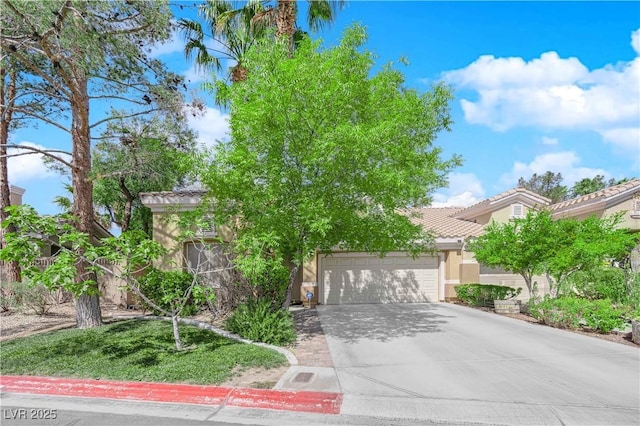 view of property hidden behind natural elements featuring an attached garage, stucco siding, a tile roof, and concrete driveway