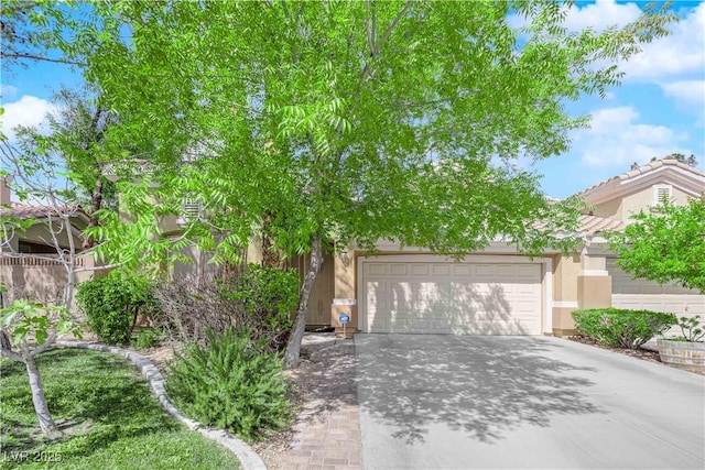 obstructed view of property featuring a tiled roof, an attached garage, driveway, and stucco siding
