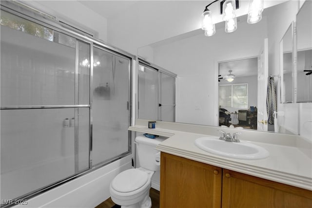 full bath with ceiling fan, vanity, toilet, shower / bath combination with glass door, and ensuite bathroom