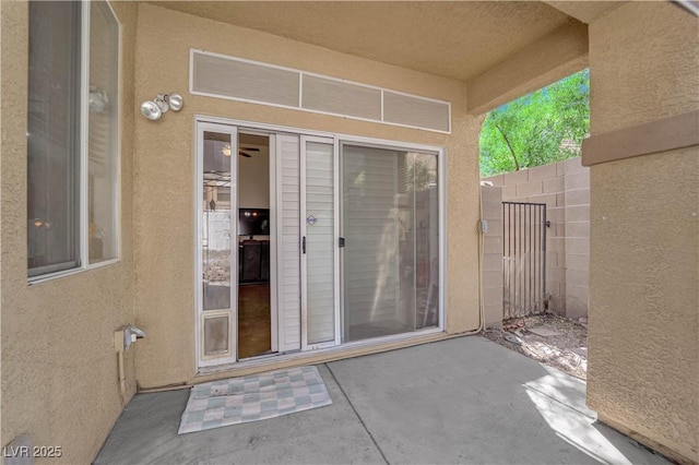 property entrance featuring a patio, fence, and stucco siding