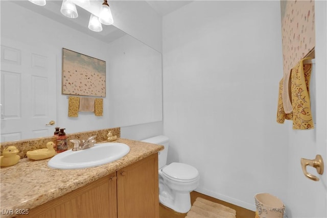 bathroom with toilet, baseboards, and vanity