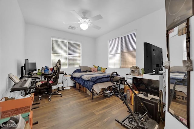 bedroom featuring a ceiling fan, visible vents, and wood finished floors