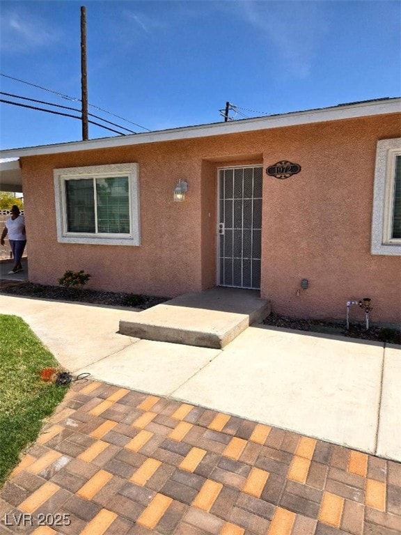 property entrance with a patio and stucco siding