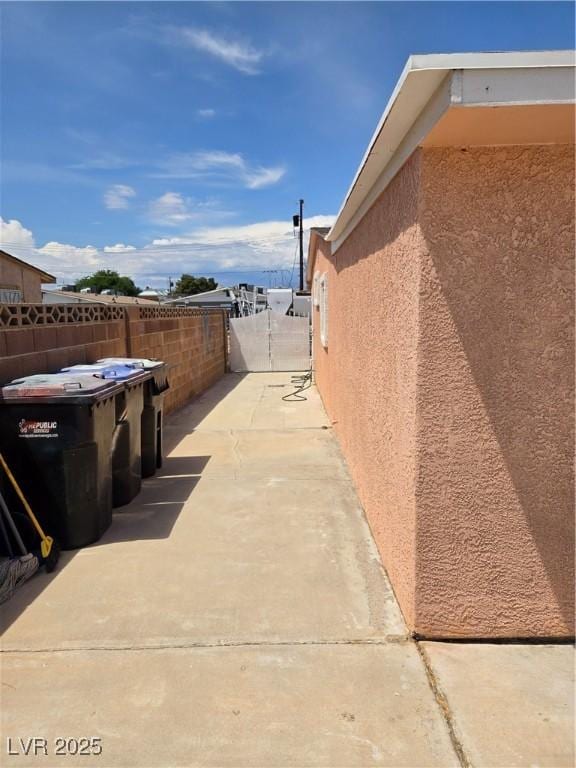 view of side of home featuring stucco siding, a gate, fence, and a patio