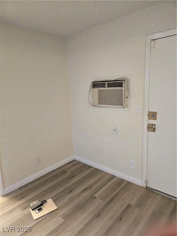 spare room with baseboards, a wall mounted air conditioner, a textured ceiling, and wood finished floors