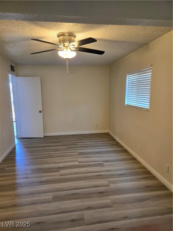spare room featuring a ceiling fan, a textured ceiling, wood finished floors, and a healthy amount of sunlight