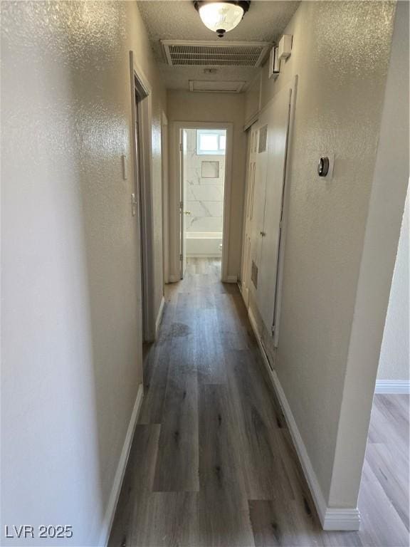 corridor featuring baseboards, visible vents, and wood finished floors