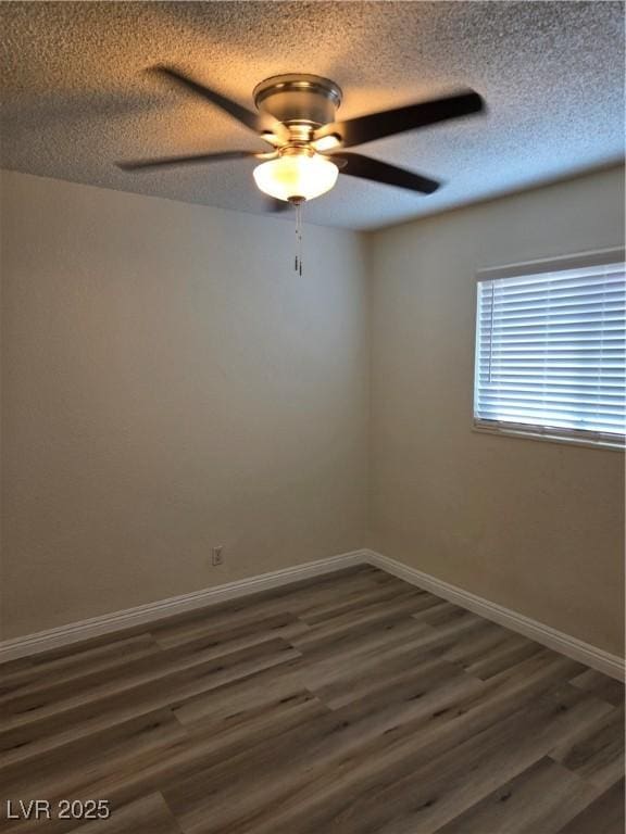 empty room with baseboards, a ceiling fan, a textured ceiling, and dark wood-type flooring