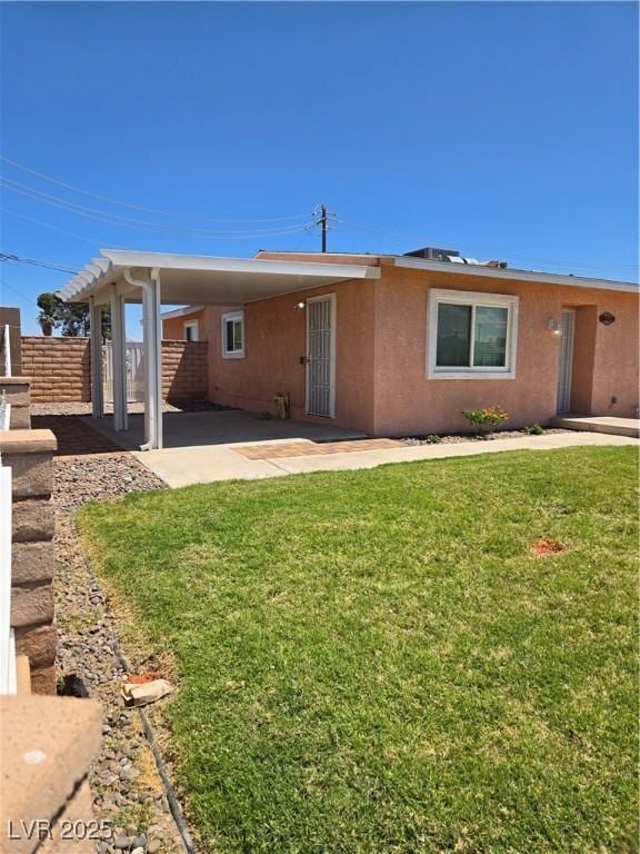 back of property with a lawn, stucco siding, and fence