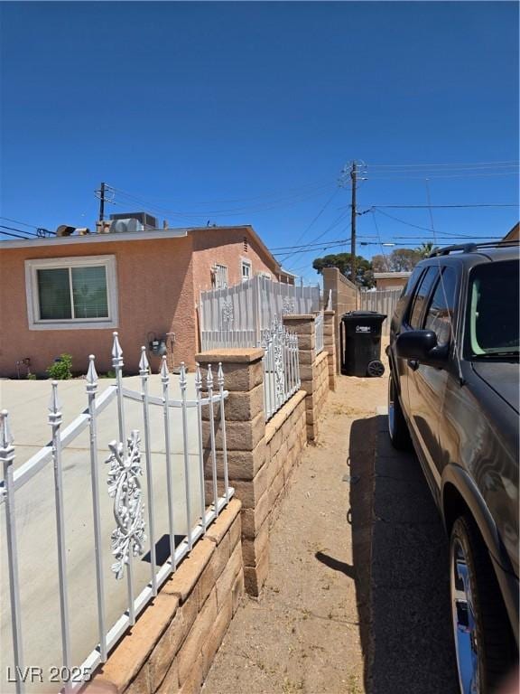 view of side of property with stucco siding and fence