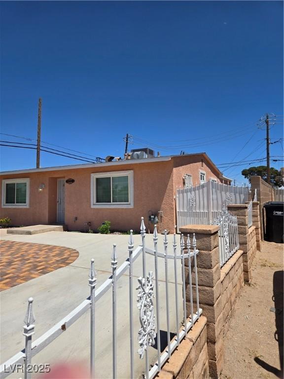 ranch-style house featuring stucco siding and fence private yard