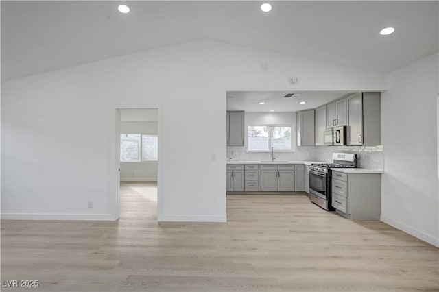 4419 Fairmont Cir, Las Vegas, NV 89147 - kitchen featuring lofted ceiling, a sink, backsplash, gray cabinetry, and stainless steel appliances