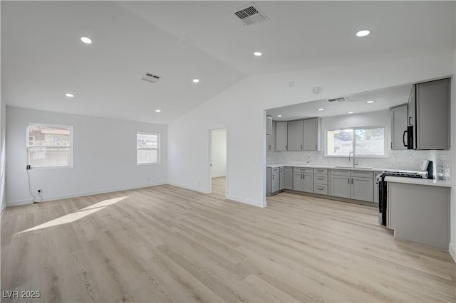 4419 Fairmont Cir, Las Vegas, NV 89147 - kitchen with stainless steel range with gas stovetop, visible vents, gray cabinets, and vaulted ceiling