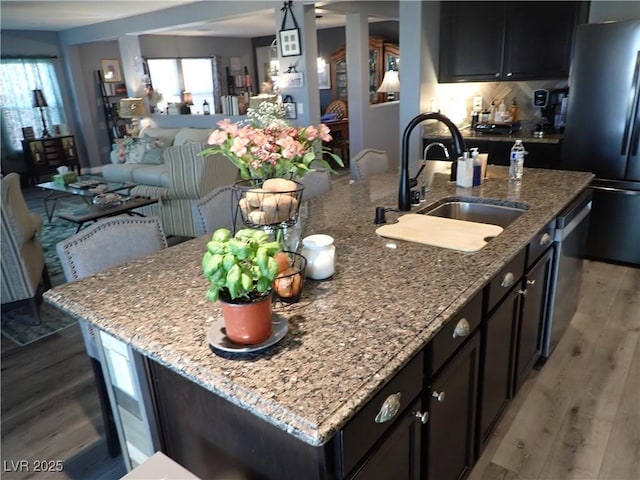 4361 Duck Harbor Ave, North Las Vegas, NV 89031 - kitchen featuring a kitchen island with sink, wood finished floors, a sink, freestanding refrigerator, and open floor plan