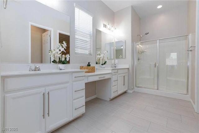bathroom with double vanity, baseboards, a shower stall, and a sink