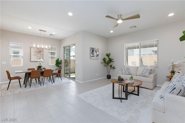 living area with visible vents, baseboards, ceiling fan with notable chandelier, and a wealth of natural light