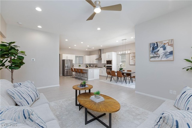living area with recessed lighting, baseboards, and ceiling fan with notable chandelier